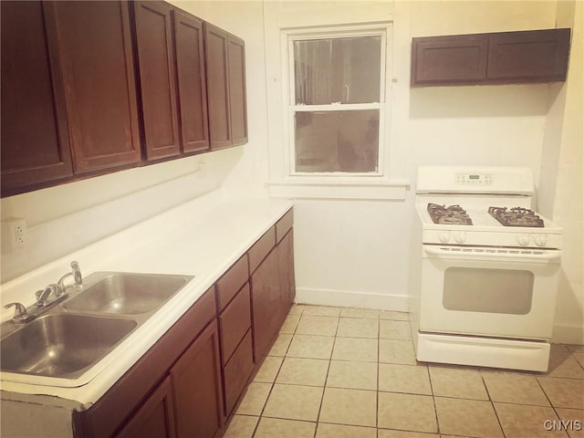 kitchen featuring light tile patterned floors, white gas range, and sink