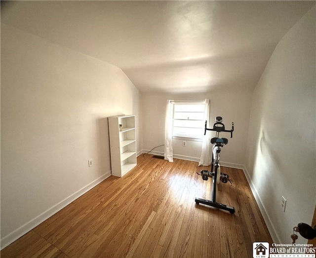 workout area featuring light hardwood / wood-style floors and vaulted ceiling