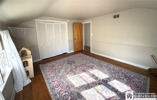 bedroom with dark wood-type flooring, a closet, and lofted ceiling