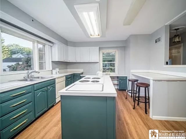 kitchen featuring white cabinets, light hardwood / wood-style flooring, a healthy amount of sunlight, and a center island