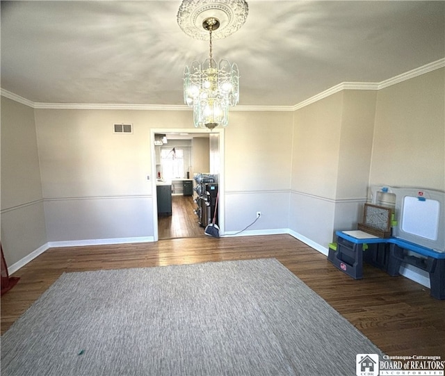 spare room featuring dark wood-type flooring, a chandelier, and crown molding