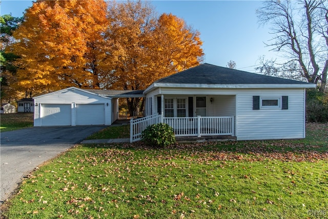 view of front facade with a front yard, covered porch, a garage, and an outbuilding