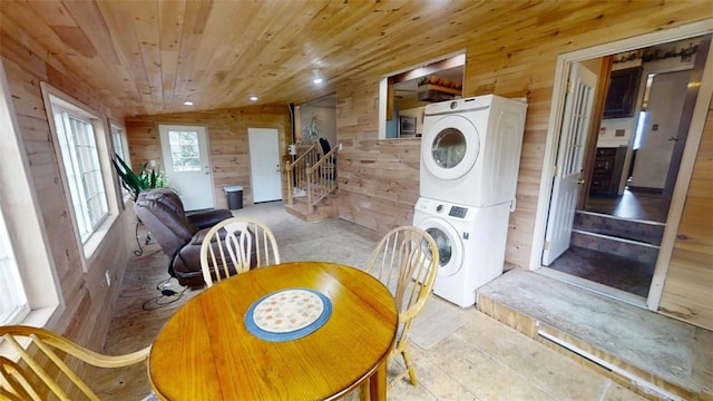 dining space with vaulted ceiling, stacked washer / dryer, wood ceiling, and wood walls