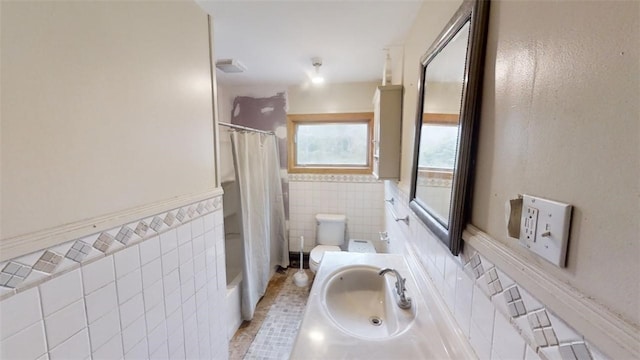 full bathroom featuring sink, shower / bath combination with curtain, toilet, tile walls, and tile patterned flooring