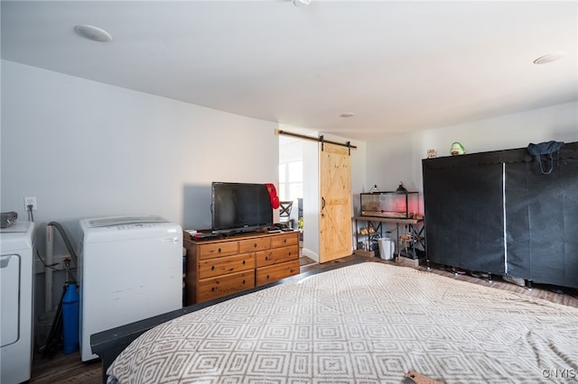 bedroom with hardwood / wood-style flooring, a barn door, and washing machine and clothes dryer