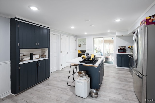 kitchen featuring a center island, a kitchen breakfast bar, stainless steel fridge, ornamental molding, and light hardwood / wood-style flooring