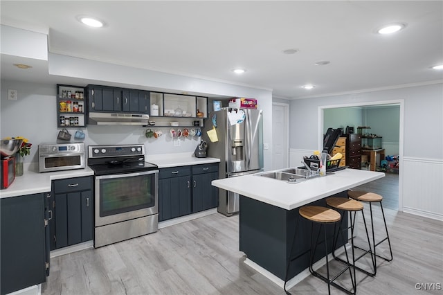 kitchen featuring light hardwood / wood-style floors, stainless steel appliances, crown molding, a breakfast bar area, and a kitchen island with sink