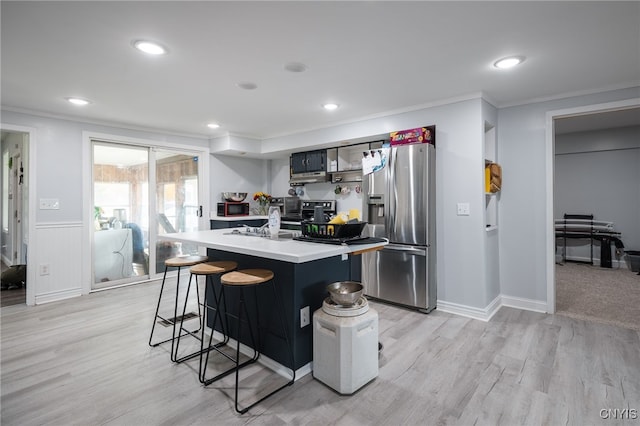 kitchen with a kitchen island with sink, light hardwood / wood-style flooring, stainless steel appliances, crown molding, and a kitchen bar