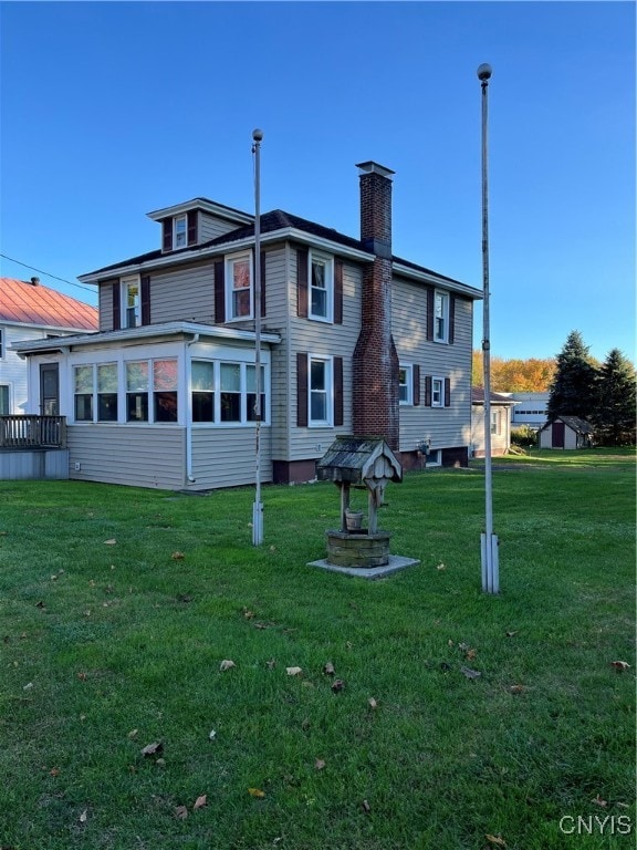 back of house featuring a yard and a sunroom