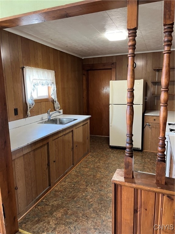 kitchen with wood walls, sink, and white refrigerator