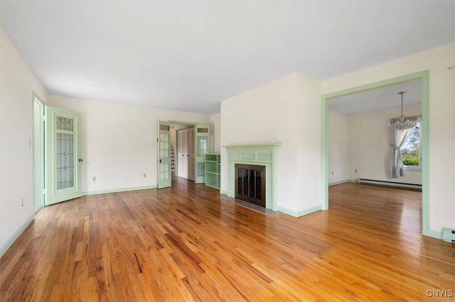 unfurnished living room with a baseboard radiator, hardwood / wood-style floors, and a notable chandelier