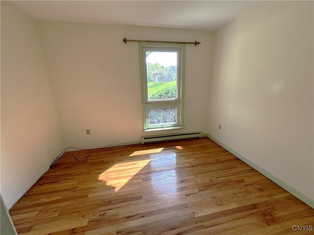 empty room with a baseboard radiator and light hardwood / wood-style flooring