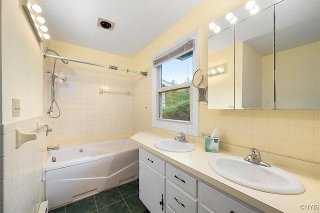 bathroom with tile walls, tile patterned flooring, tiled shower / bath combo, and vanity