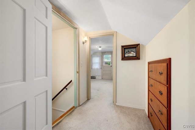 hall with a baseboard heating unit, vaulted ceiling, and light colored carpet