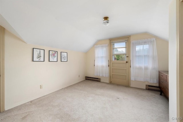 additional living space with a baseboard radiator, vaulted ceiling, and light carpet