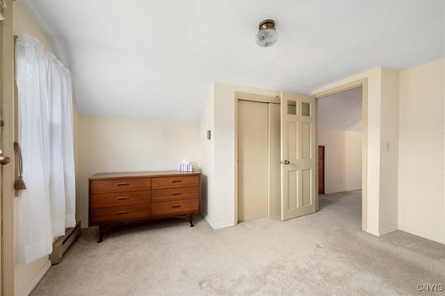 unfurnished bedroom with a baseboard radiator, light colored carpet, a closet, and vaulted ceiling