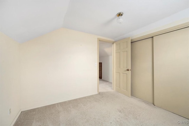 unfurnished bedroom featuring light carpet, vaulted ceiling, and a closet