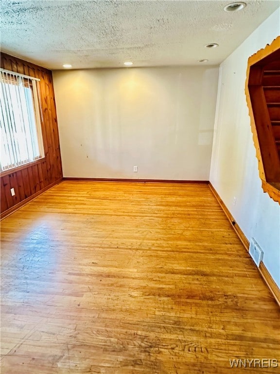 unfurnished room with a textured ceiling and light wood-type flooring