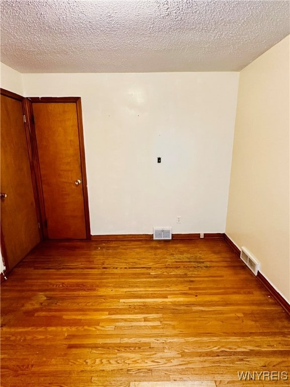 unfurnished room with a textured ceiling and light hardwood / wood-style floors