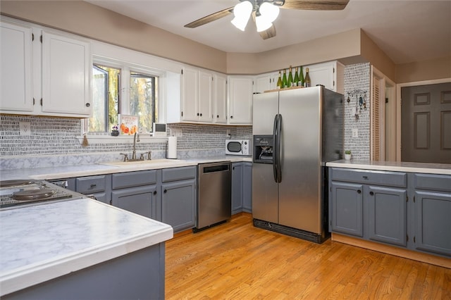 kitchen with tasteful backsplash, appliances with stainless steel finishes, white cabinetry, light wood-type flooring, and gray cabinetry