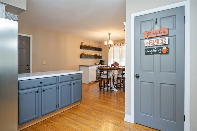 kitchen with a notable chandelier, blue cabinets, hanging light fixtures, and light wood-type flooring