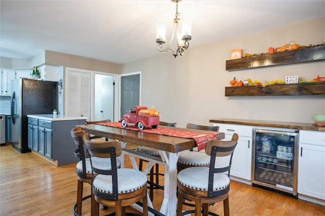 dining area with a notable chandelier, light wood-type flooring, and beverage cooler