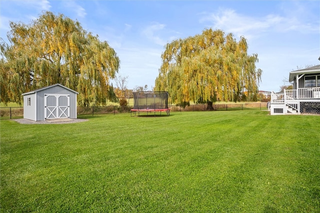 view of yard with a wooden deck, a storage shed, and a trampoline