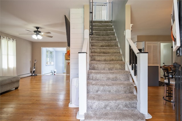 staircase with ceiling fan, wood-type flooring, and a baseboard radiator