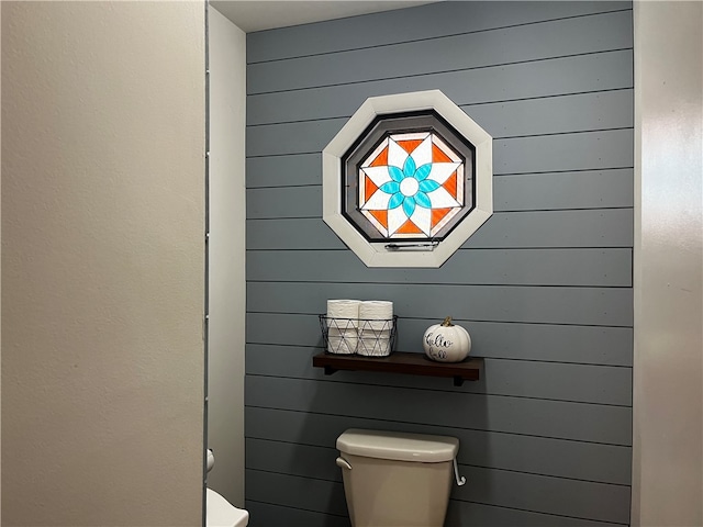 bathroom with toilet and wood walls