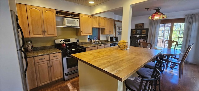 kitchen with dark hardwood / wood-style flooring, wooden counters, a center island, and white appliances