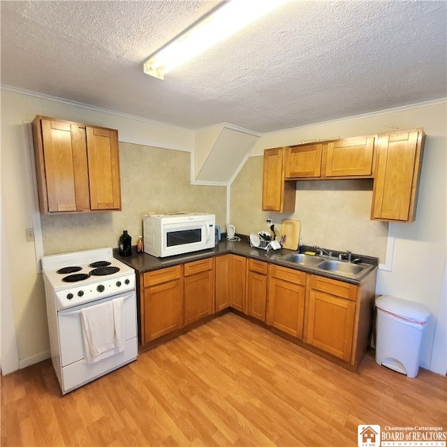 kitchen featuring sink, a textured ceiling, light wood-type flooring, and white appliances