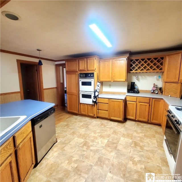 kitchen featuring white appliances, wood walls, sink, pendant lighting, and ornamental molding