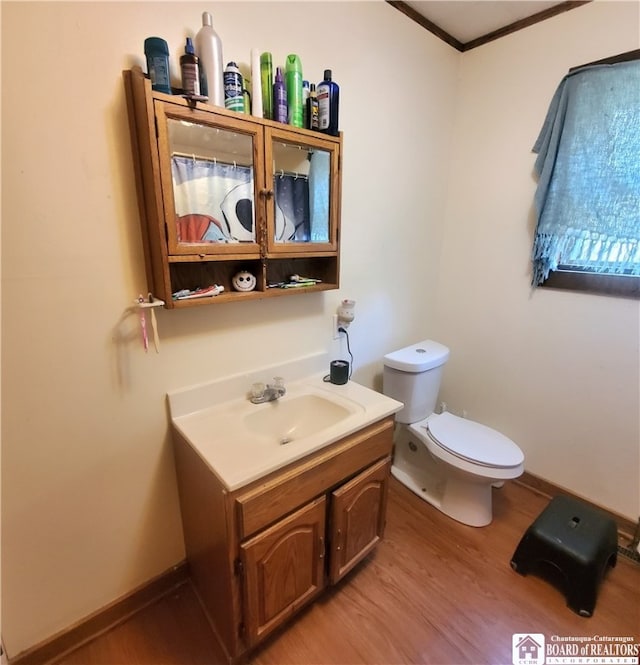 bathroom featuring toilet, ornamental molding, vanity, and wood-type flooring