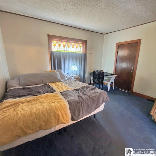 bedroom with a textured ceiling and dark colored carpet