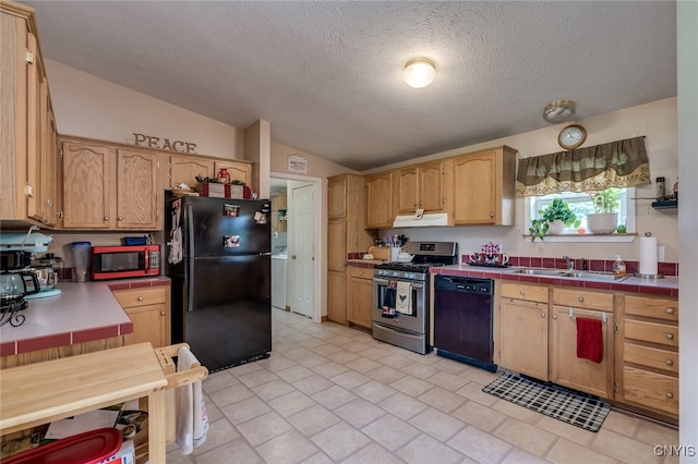 kitchen featuring sink, vaulted ceiling, black appliances, a textured ceiling, and tile countertops