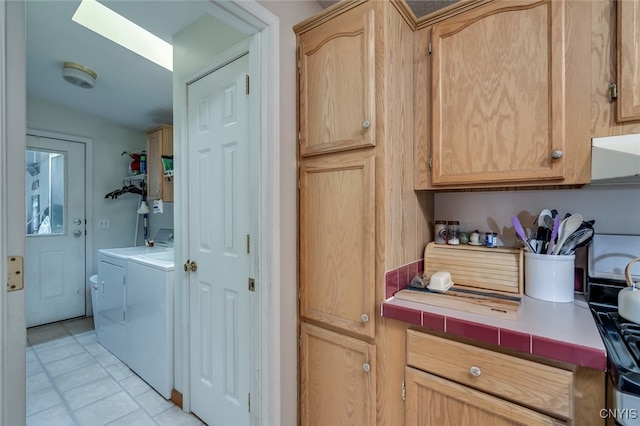 washroom with light tile patterned floors, washing machine and dryer, and cabinets