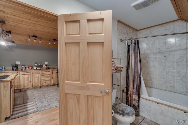 bathroom featuring tile patterned flooring, vaulted ceiling, shower / bath combination with curtain, and toilet