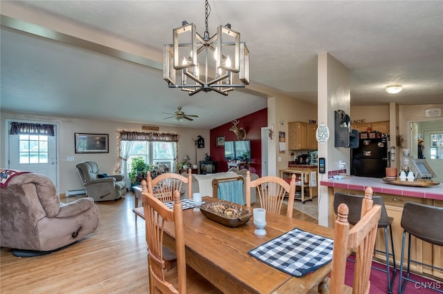 dining space with ceiling fan with notable chandelier, vaulted ceiling, light hardwood / wood-style flooring, and a baseboard heating unit