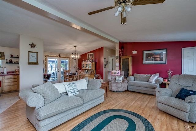 living room featuring vaulted ceiling, ceiling fan with notable chandelier, light hardwood / wood-style floors, and french doors