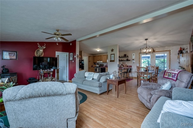 living room featuring ceiling fan with notable chandelier, vaulted ceiling, and light hardwood / wood-style floors