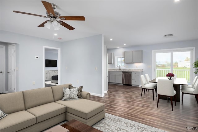 living room featuring ceiling fan, sink, and dark hardwood / wood-style floors