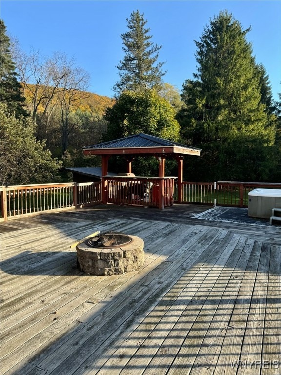 deck featuring a hot tub, a gazebo, and a fire pit