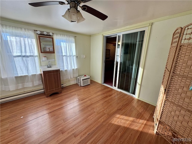 interior space featuring ceiling fan, wood-type flooring, ornamental molding, and baseboard heating