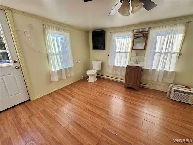 interior space with light hardwood / wood-style flooring, a baseboard heating unit, a healthy amount of sunlight, and ceiling fan