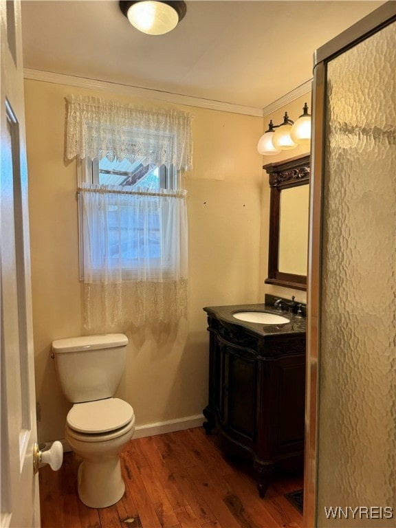 bathroom with vanity, toilet, wood-type flooring, and ornamental molding