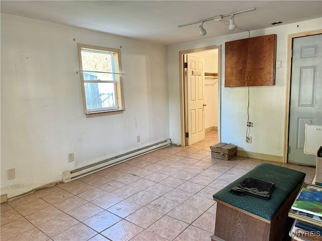 spare room with baseboard heating, light tile patterned flooring, and rail lighting