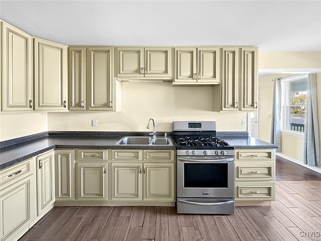 kitchen with cream cabinets, dark hardwood / wood-style floors, stainless steel range with gas cooktop, and sink