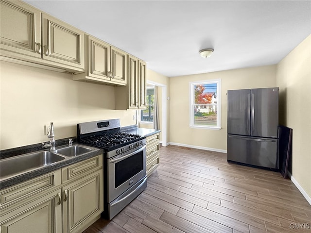 kitchen featuring appliances with stainless steel finishes, sink, wood-type flooring, and cream cabinetry