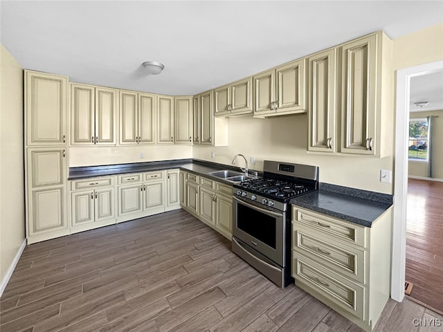 kitchen featuring sink, gas stove, cream cabinets, and dark hardwood / wood-style flooring