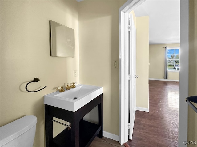 bathroom with toilet, vanity, and wood-type flooring